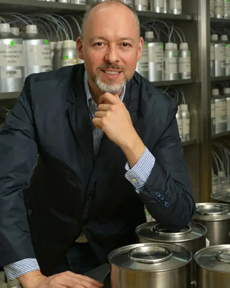 Jorge Lee seated in a perfumery laboratory among stainless-steel fragrance vessels