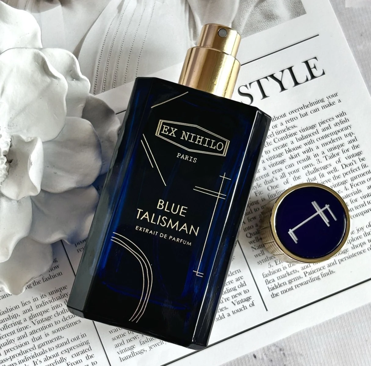 Blue Talisman Extrait bottle on a fashion magazine with white sculpture