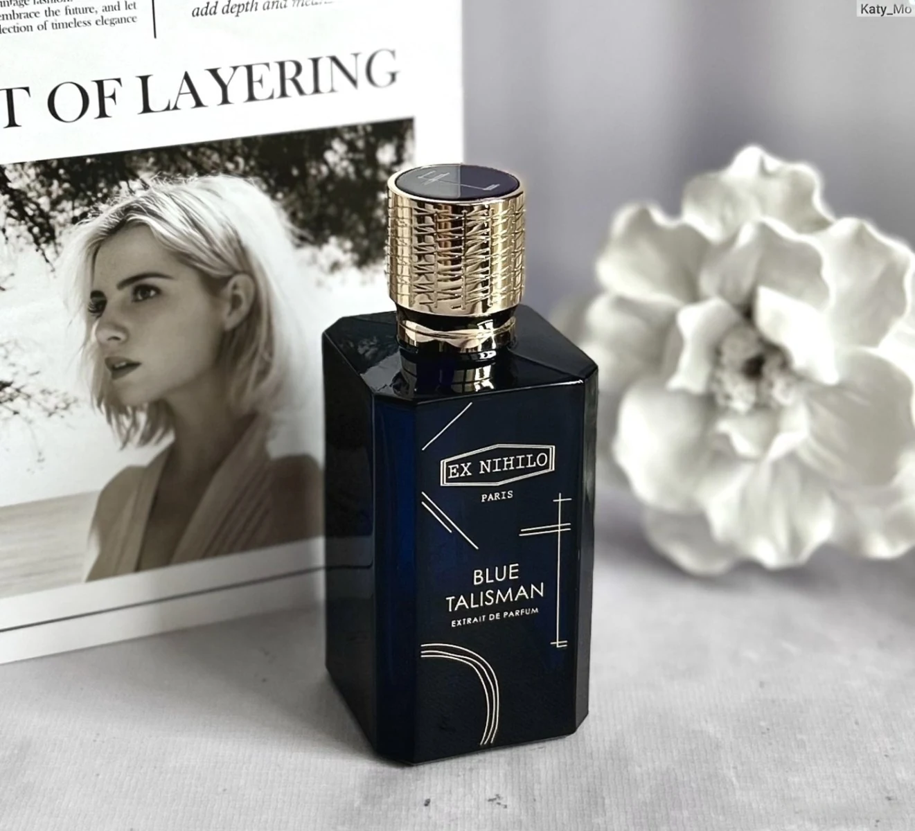 Blue Talisman Extrait bottle beside monochrome portrait